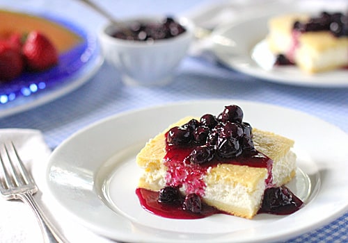 clean white plate with square yellow pastry filled with cream cheese and topped with blueberry sauce