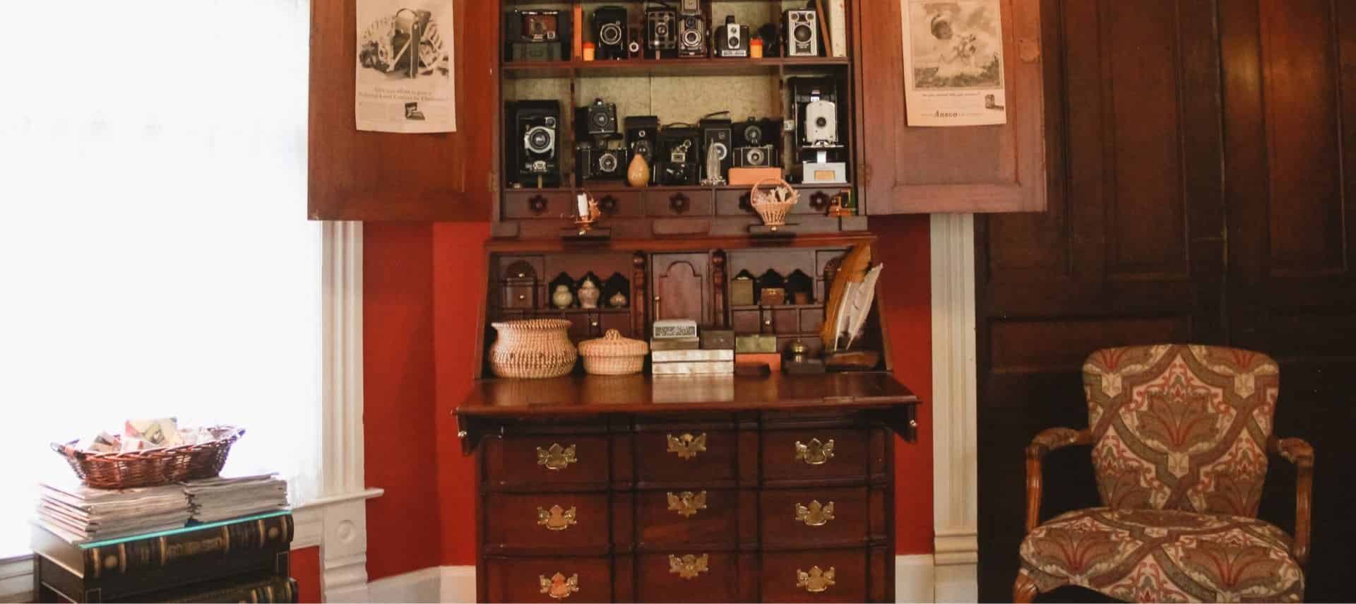 Antique dark wooden desk with hutch on top filled with antique cameras